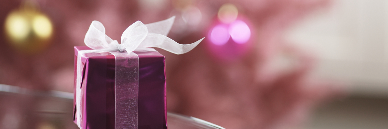 Surviving the Holidays With Asperger's and Fibromyalgia Small pink gift box on edge of table.