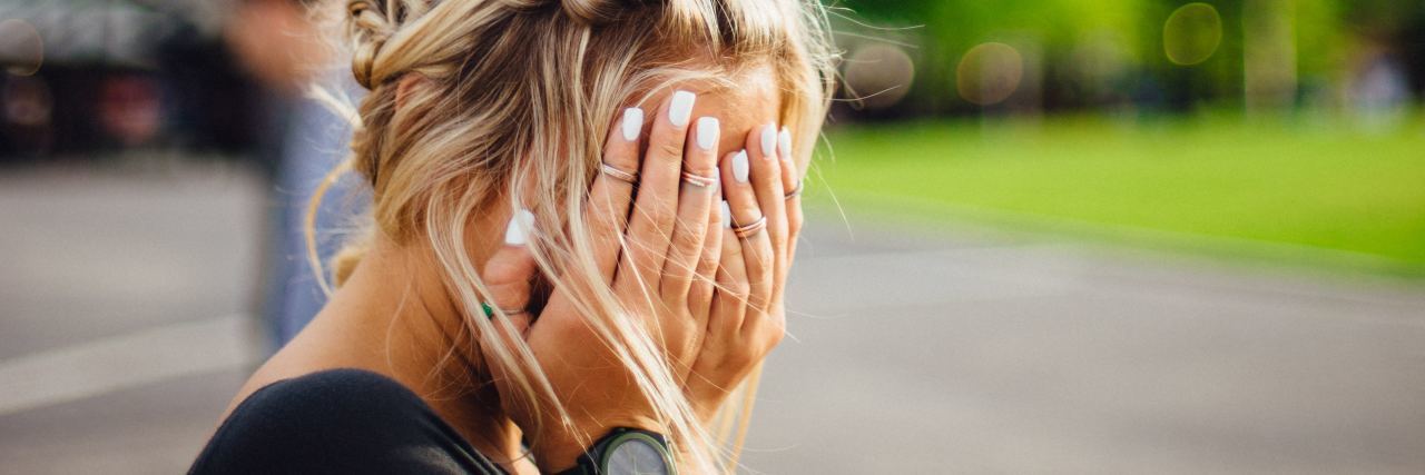 blonde college student covering face with hands