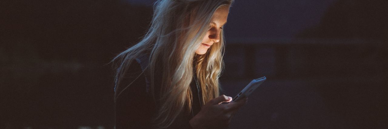 blonde woman at night looking at phone