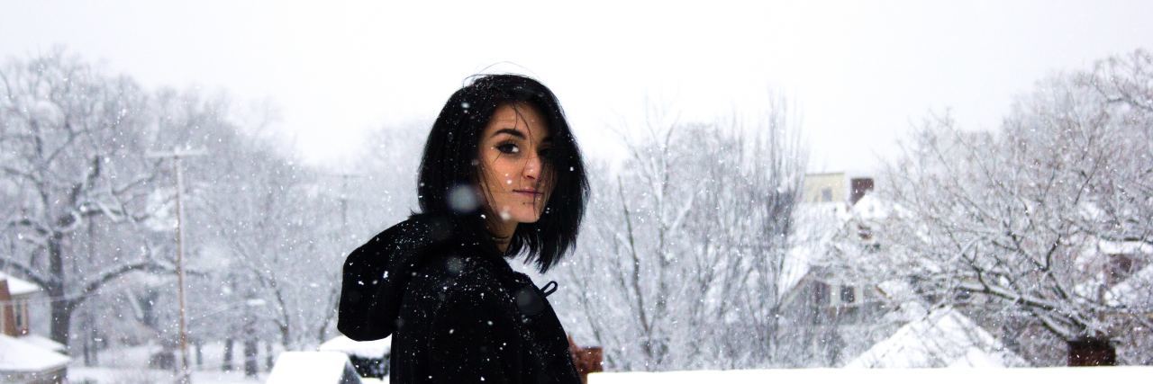 teenager with short black hair stands outside in the snow