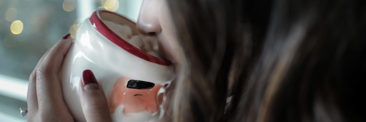 How to Cope With Anxiety During the Holiday Season woman drinking hot chocolate from santa mug at christmas