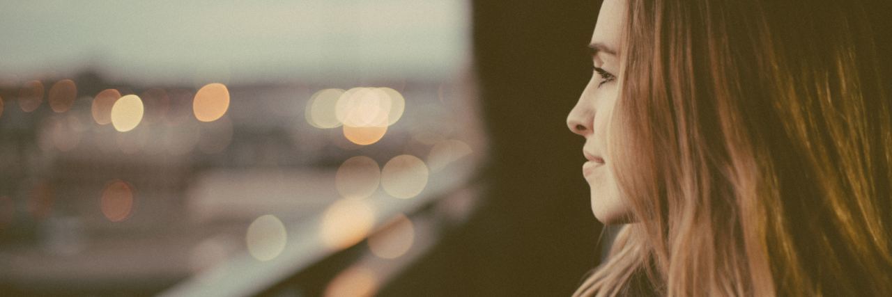 happy woman looking out of balcony over city