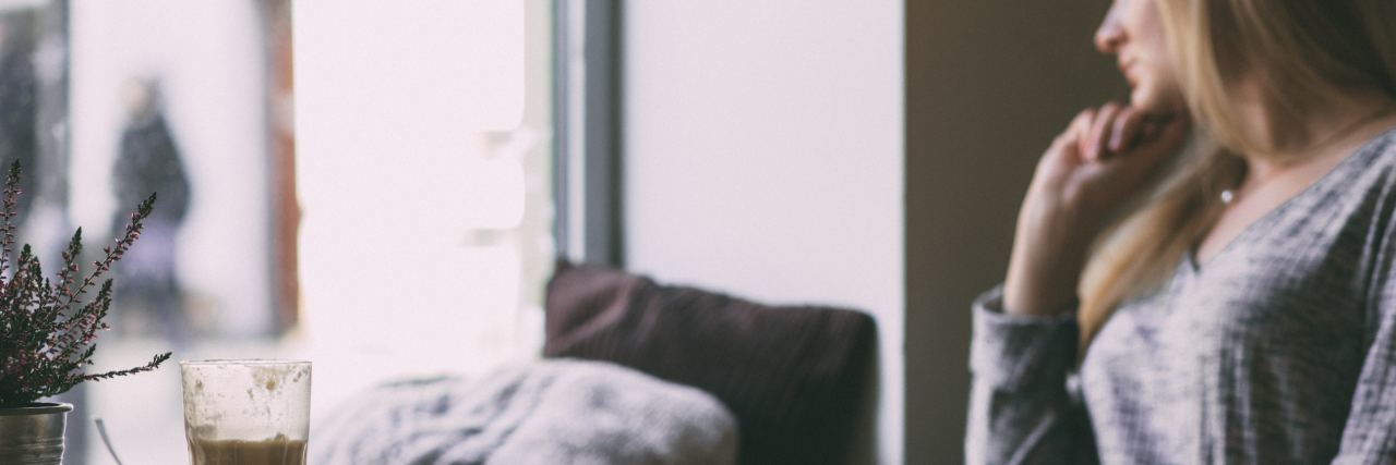 Loneliness Is One of Depression's Most Difficult Symptoms woman alone in coffee shop looking pensive