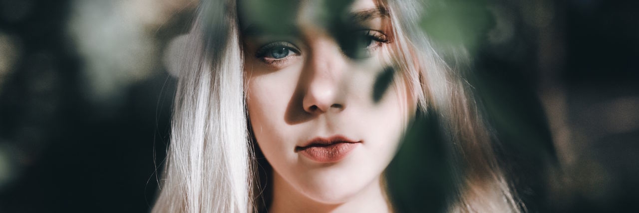 Why I Self-Sabotage as Someone With Borderline Personality Disorder woman face behind tree