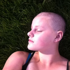 A photo of the writer, laying in the grass, without any hair.