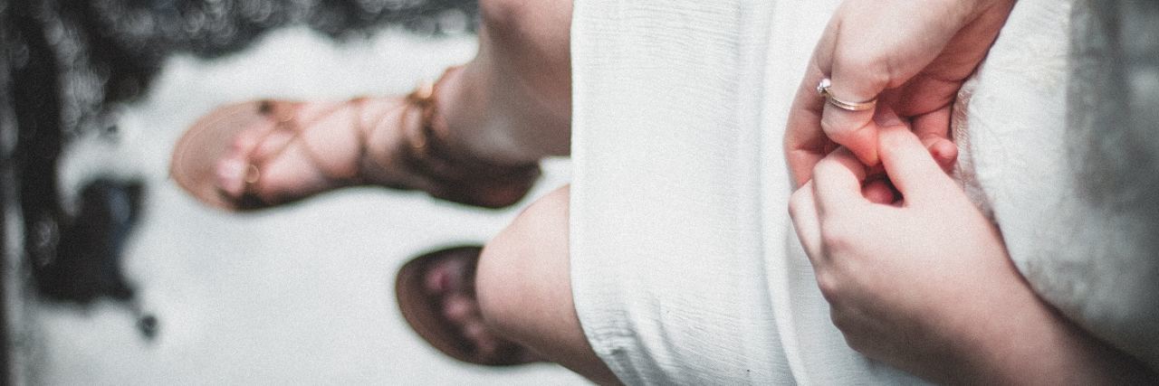 Why I Feel Violated by Intrusive Thoughts and Pure OCD girl sitting on edge of waterfall holding hands delicate