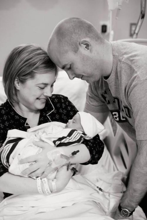 Black and white image of couple holding a baby with Down syndrome