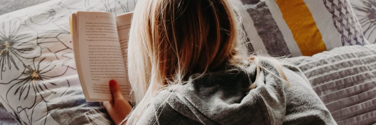 Healthy Ways to Self-Soothe Anxiety blonde woman lying on bed reading book