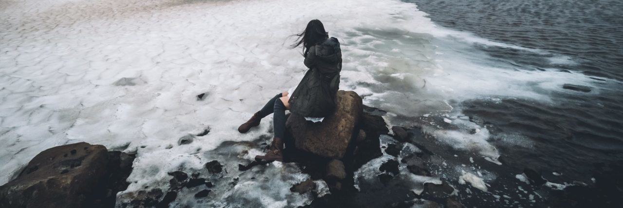 Finding Healing in the Numb of Borderline Personality Disorder woman sitting in ice and ocean on rock in iceland gray color