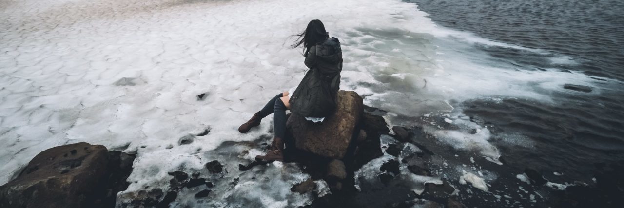 woman sitting in ice and ocean on rock in iceland gray color