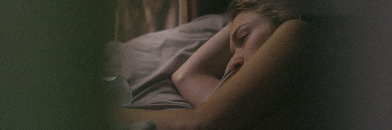 When Depression Makes You Stay in Bed woman lying in bed mostly in darkness