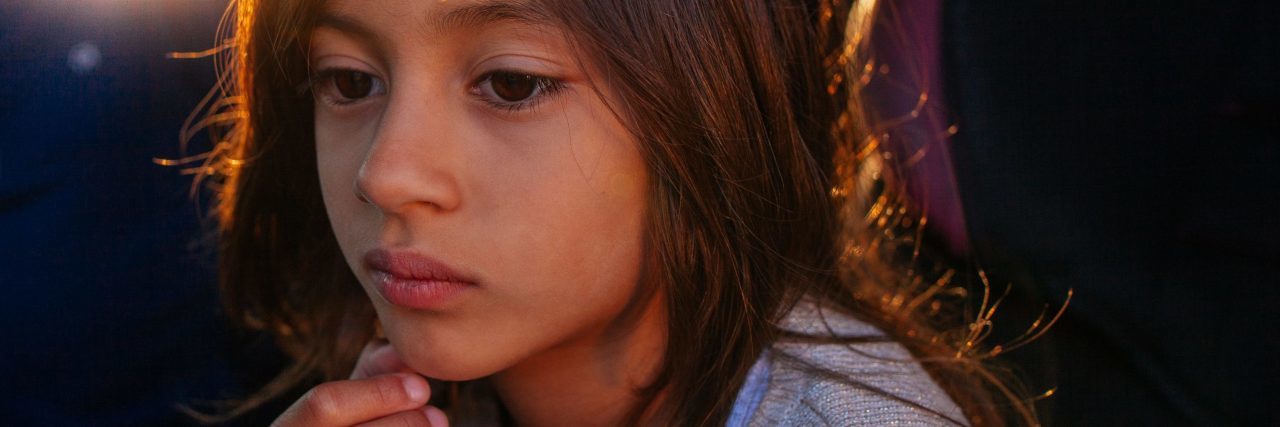 How OCD Affected Me As a Child young girl looking upset or pensive with fingers on chin