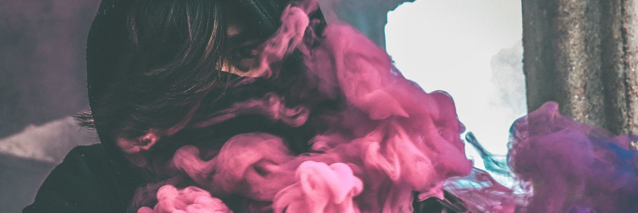 woman with pink and blue smoke surrounding her