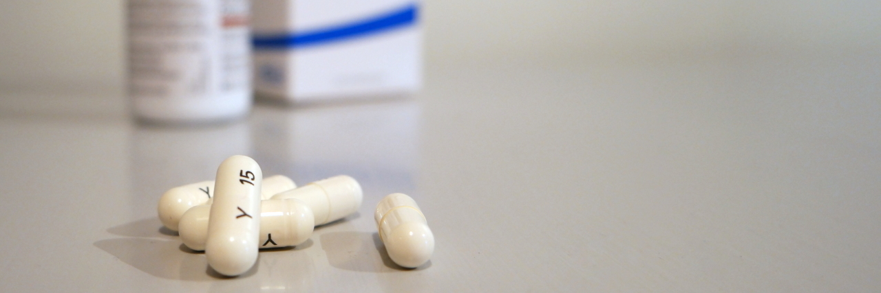 pills on white surface next to pill bottle and box