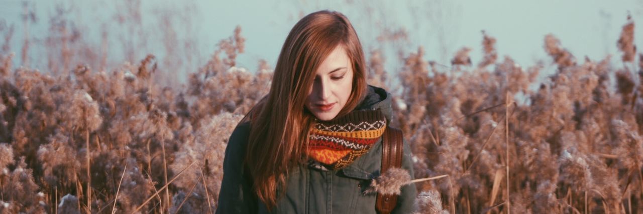 Why I Would Never Remove My Self-Harm Scars woman with red hair stands in field during a fall day