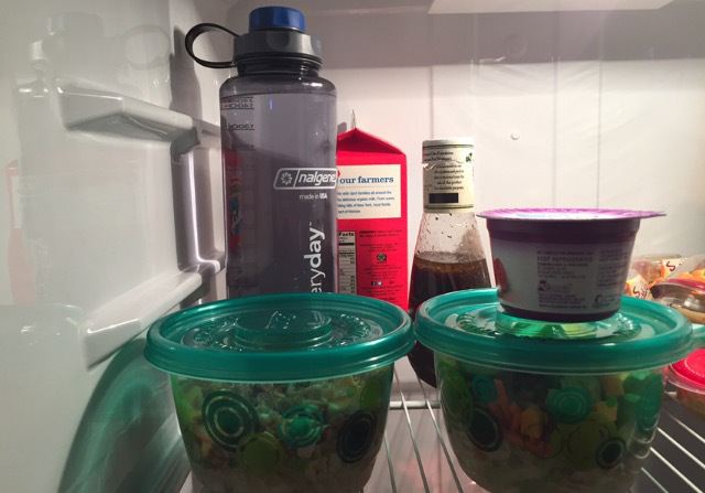 two salads in the fridge with a water bottle