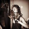 A photo of Nicole singing into a mic, recording a song.