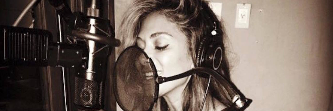 A photo of Nicole singing into a mic, recording a song.