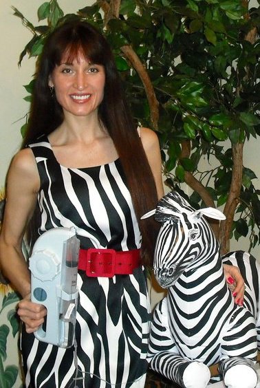 woman in a zebra print dress holding a stuffed zebra and medical supplies