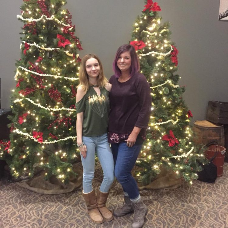 two women standing in front of christmas trees