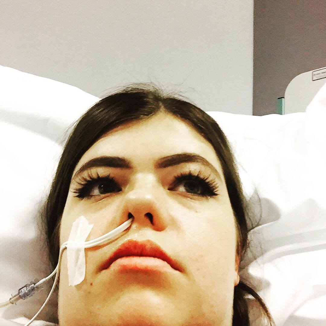 The writer laying in a hospital bed with a tube in her nose.