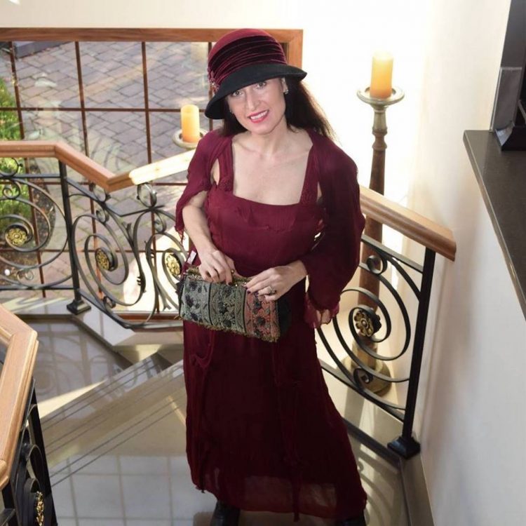 woman dressed up in a hat and dress holding a purse