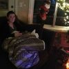 woman wrapped in a blanket on the sofa next to a christmas tree