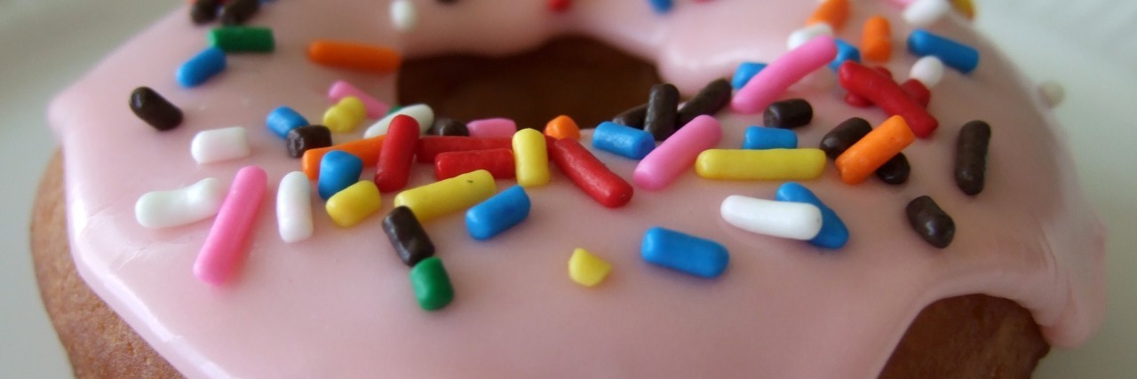 Craving Food You Can't Eat and Fearing Your Next Meal Due to IBD close up photo of a donut with pink frosting and sprinkles