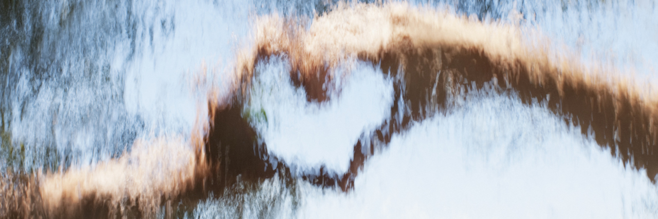 Hands making heart shape behind distorted glass