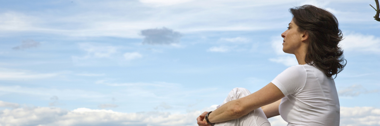 When My Doctor Unexpectedly Delayed My Chiari Malformation Surgery woman sitting on a wall overlooking the scenery