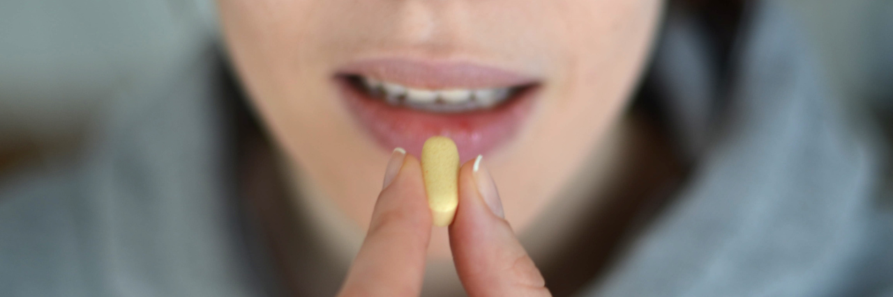 woman taking large yellow pill