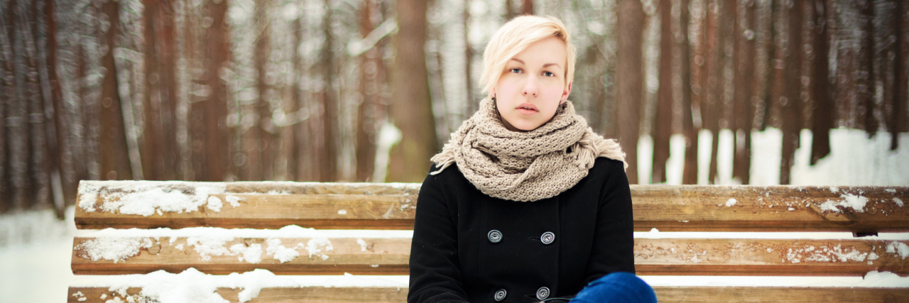 Why Wanting Quiet Time During the Holidays Doesn’t Mean I’m a ‘Grinch’ Young blonde woman sitting on a bench in winter park