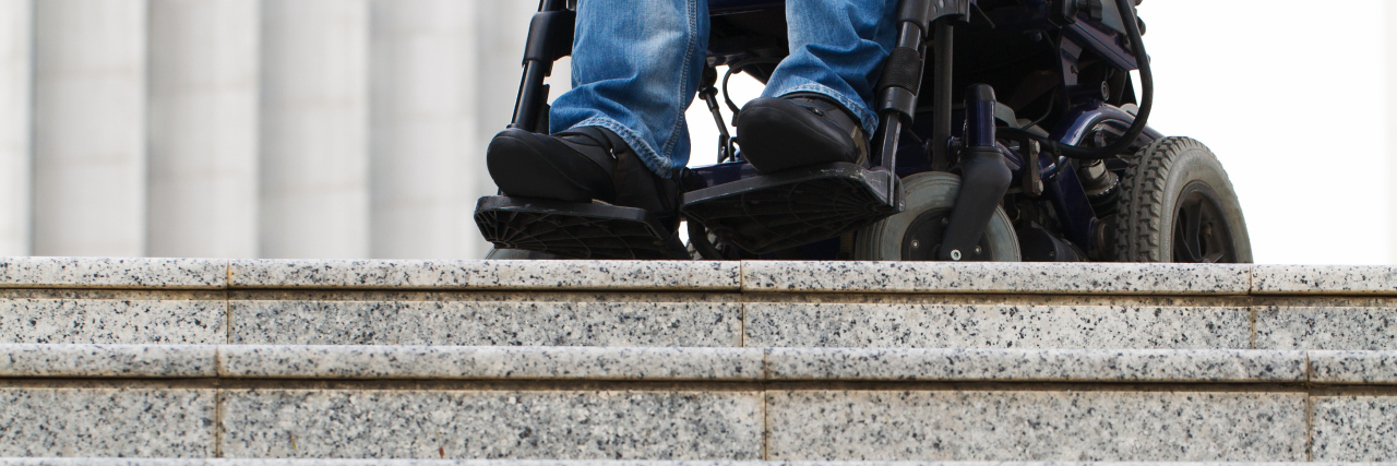 How the Disability Community Is Counted Out by Society Wheelchair user in front of staircase barrier.