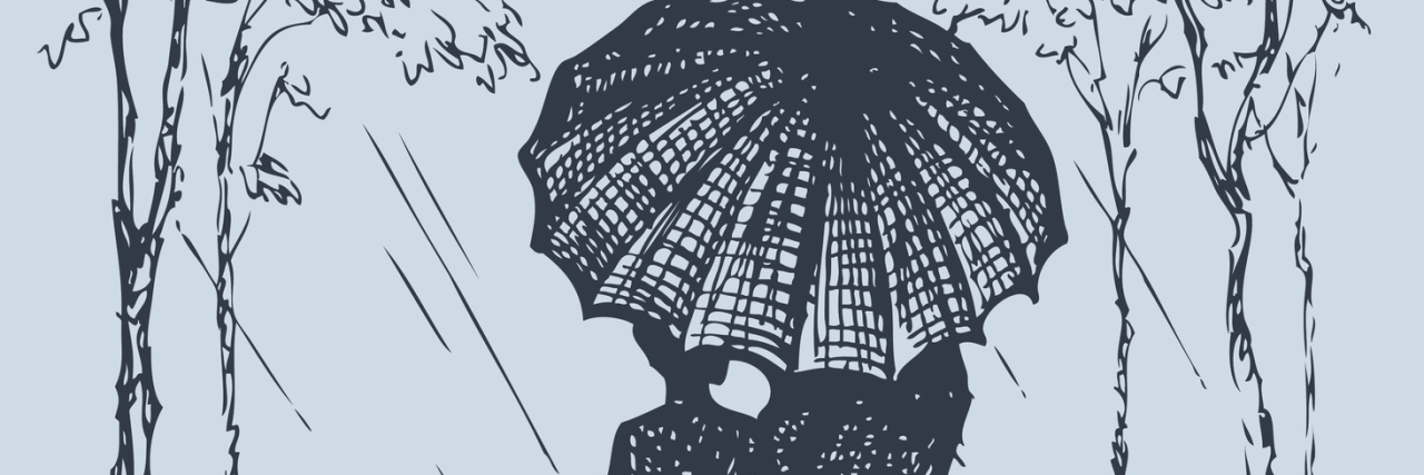 The Truth About Love When You Have a Chronic Illness A couple walking down a road as rain falls own and they're covered by an umbrella.