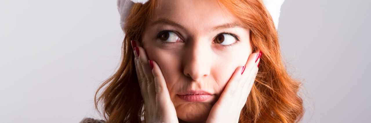 8 Things in My Mental Health Kit for the Holidays Young red head woman sad emotion, expression and looking her right, wearing christmas hat, isolated on white background.