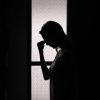 silhouette of a woman holding her head in a dark room