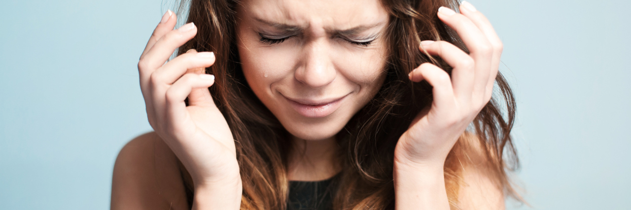 woman crying against pale bluye background