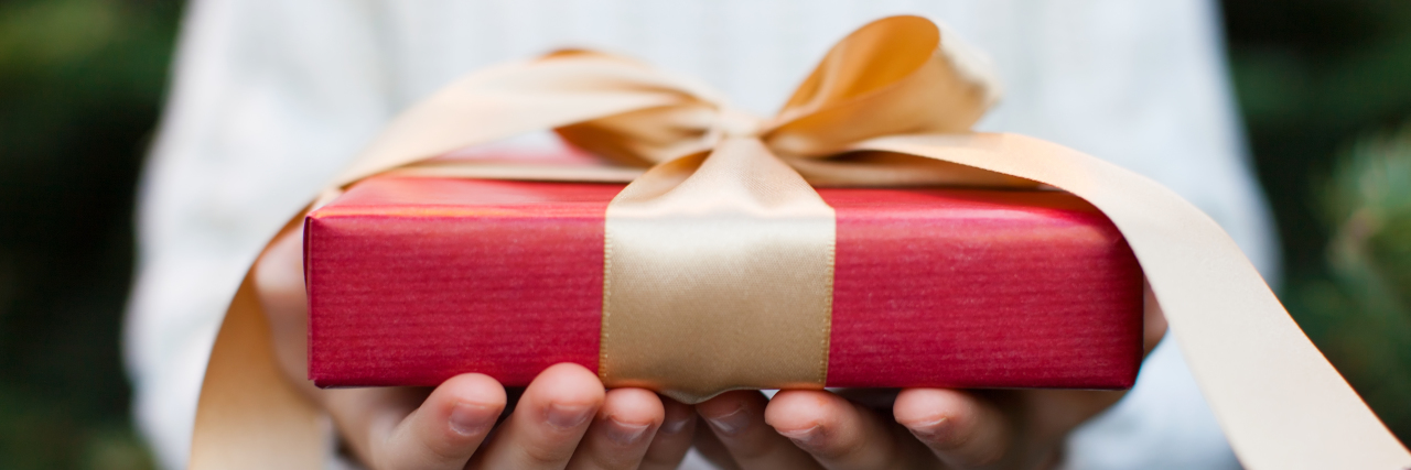 Holiday Gift Ideas for a Loved One With Chronic Pain woman holding christmas present