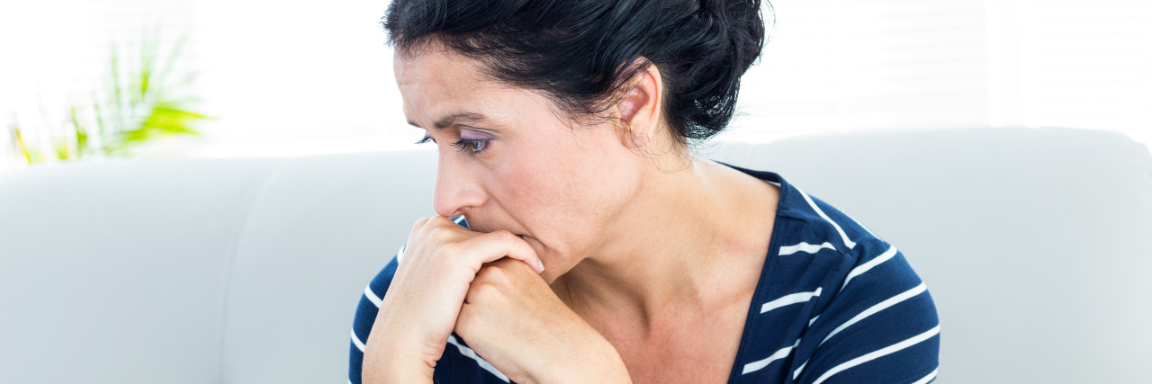 When You're Relearning the Art of Saying 'No' as Someone With PTSD Unhappy woman sitting on the couch on white background