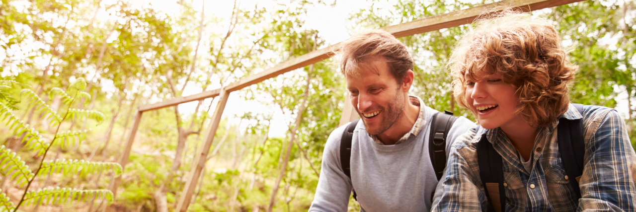 How to Understand Others With Chronic Illness Father and son sitting on a bridge in a forest, close up