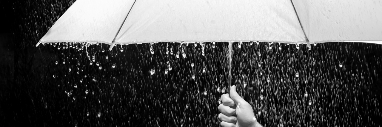 Why Harvard's Study About Rain and Pain Is Flawed Hand holding an umbrella in rain, black background - business and fashion concept.