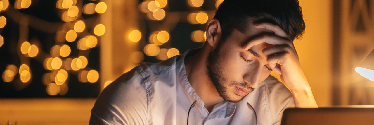 What to Remember If Depression or Anxiety Makes Christmas Hard man alone at christmas working at computer exhausted or depressed