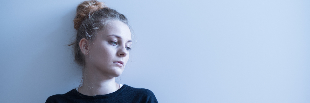 9 Ways to Get Through a Bad Mental Health Day Photo of a depressed girl sitting with crossed arms