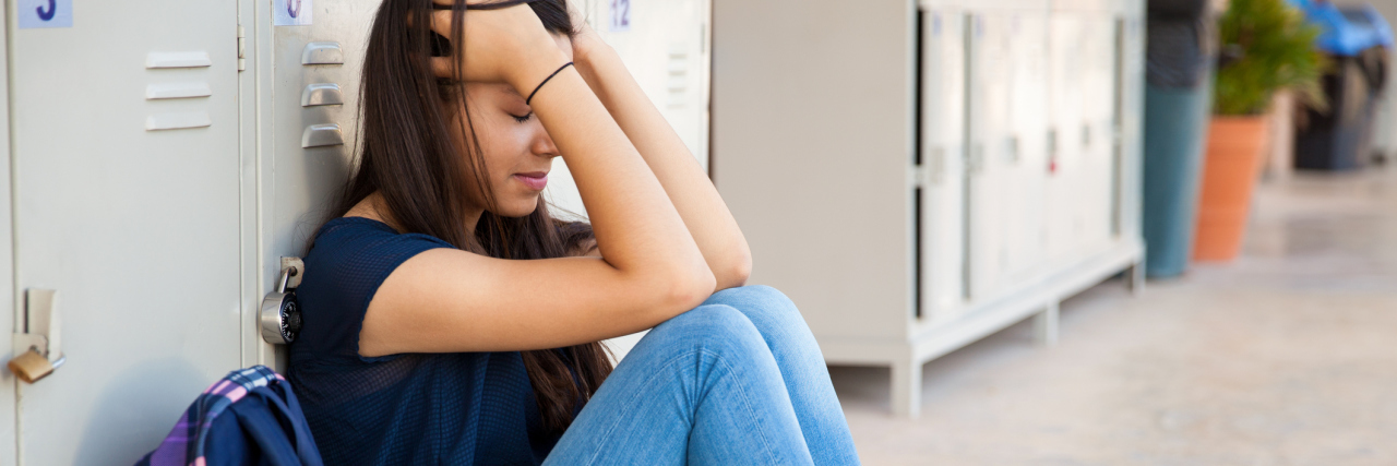 What My Teachers Need to Know About My Anxiety high school girl sitting with back to lockers anxious or stressed out