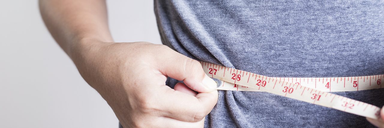 Person measuring their waistline