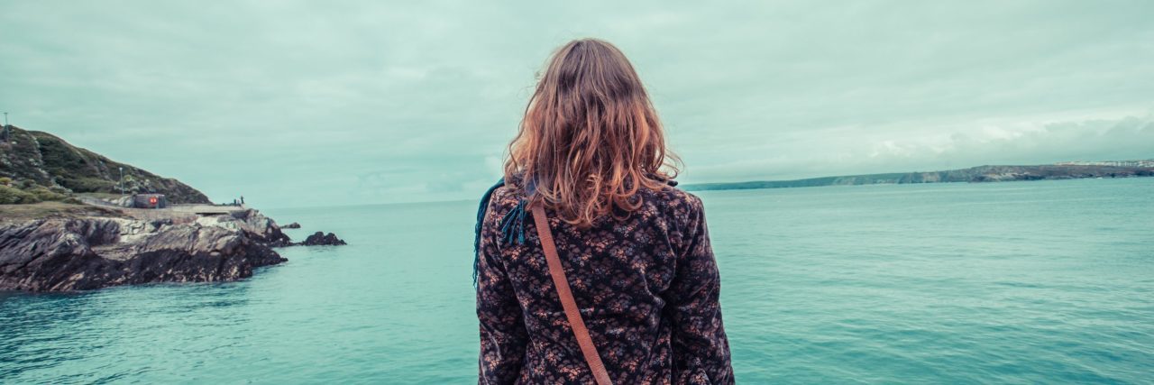 When Depression Makes You Feel Isolated From the Rest of the World young woman sitting at water's edge by harbour isolated