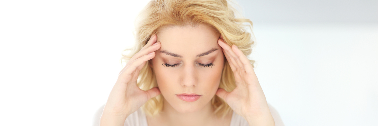 A Day With Hashimoto's Thyroiditis A woman with her head in her hands - looking stressed.