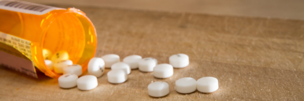 What It Means for Chronic Pain Patients That DEA Cut 2018 Opioid Quota White pills spilled out over some wood