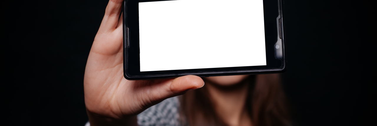 What It Looks Like to Live With Chronic Pain woman taking a photo of herself on her phone