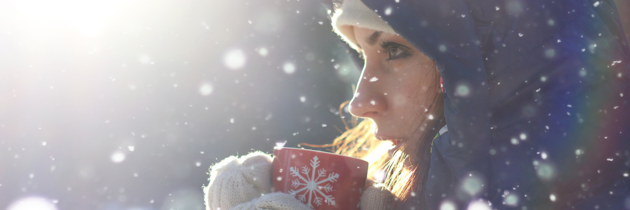 woman drinking from a red mug outside in the snow
